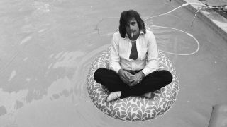 Eddie Money sits fully clothed on a rubber raft in his backyard pool.