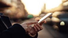 A woman uses her smartphone, a city's silhouette in the background.