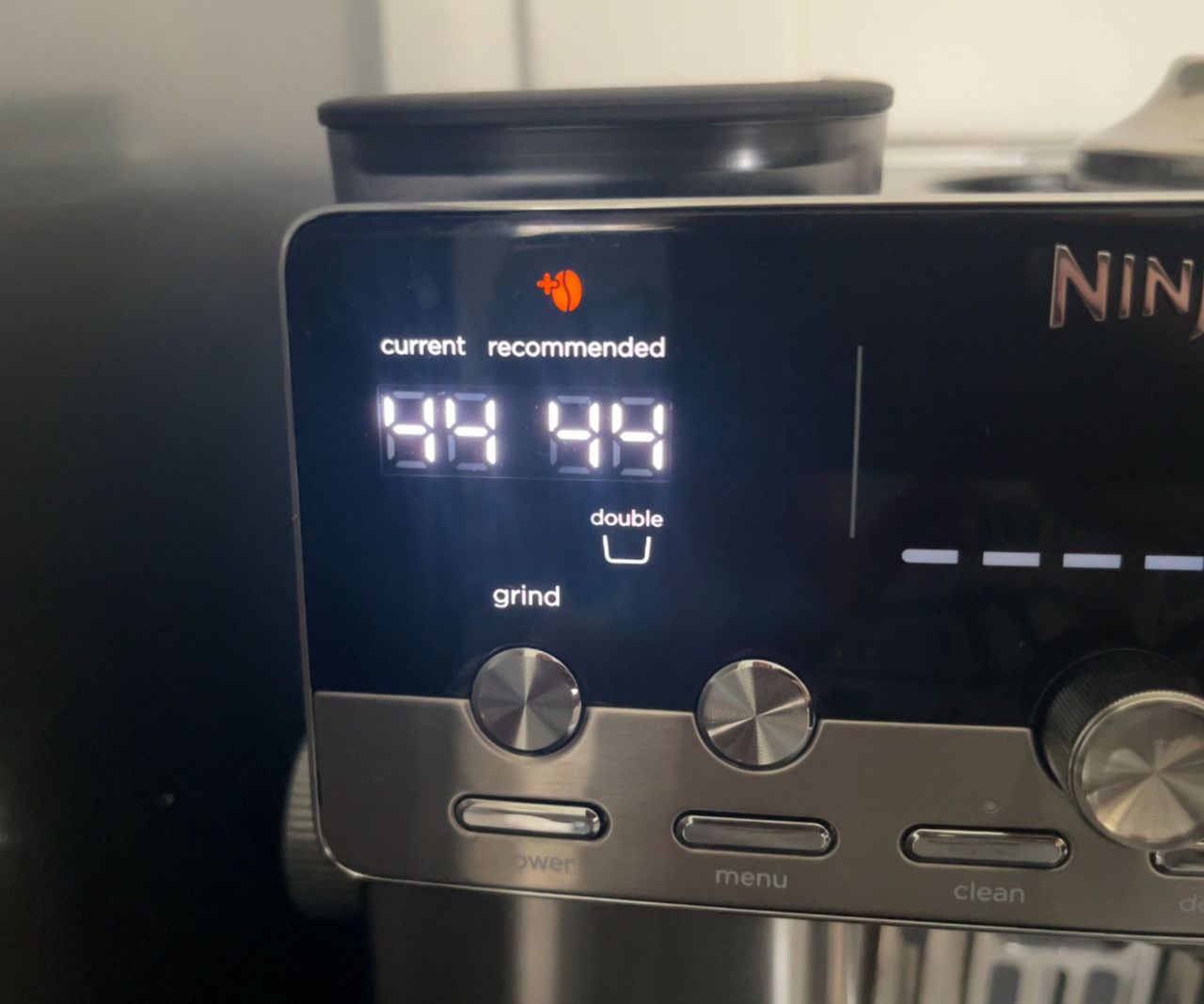 A red 'add bean' symbol illuminated on the LED screen of the ninja luxe caf&eacute; mini espresso machine.