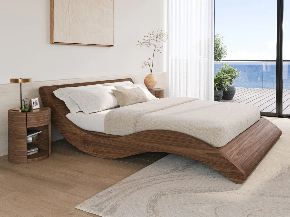 coastal bedroom with light timber floorboards, gray rug, timber side tables with lamp, artwork above bed, vase with branch, and curved timber bedframe