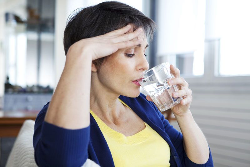 A woman with a hot flash drinking water