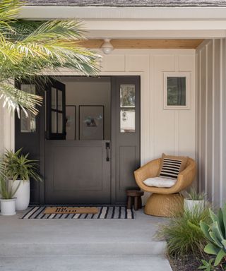 Porch with rattan armchair, welcome mat, palm trees and black dutch doors