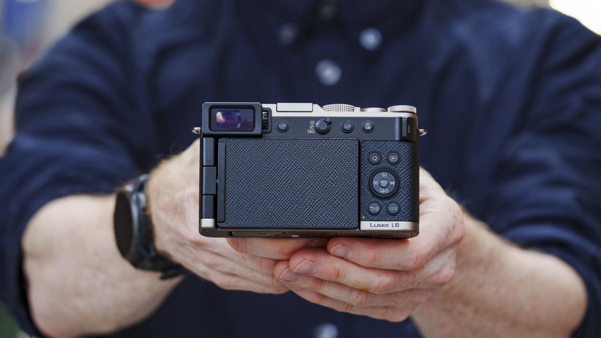 Man holding the Panasonic Lumix L10 compact camera in an urban setting of Japan