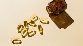Cod liver oil capsules in a glass jar scattered