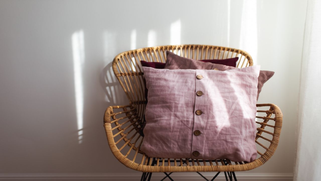 Pink envelope cushion on a whicker chair