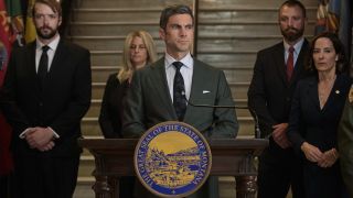 Wes Bentley as Jamie Dutton standing behind a podium with four people standing behind him in Yellowstone. 