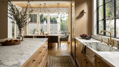 beautiful open plan kitchen with marble counters, wooden cabinetry, and bronzed hardware