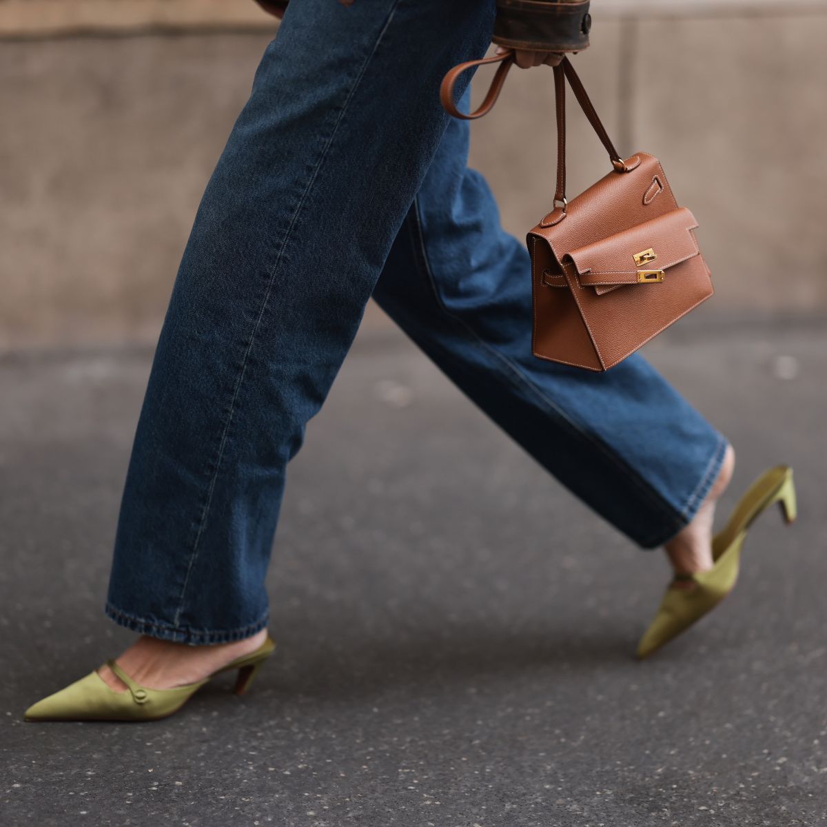 a close up of a woman wearing green everyday heels, jeans and a brown hermes bag