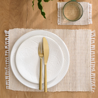 A beige placemat with plates and cutlery