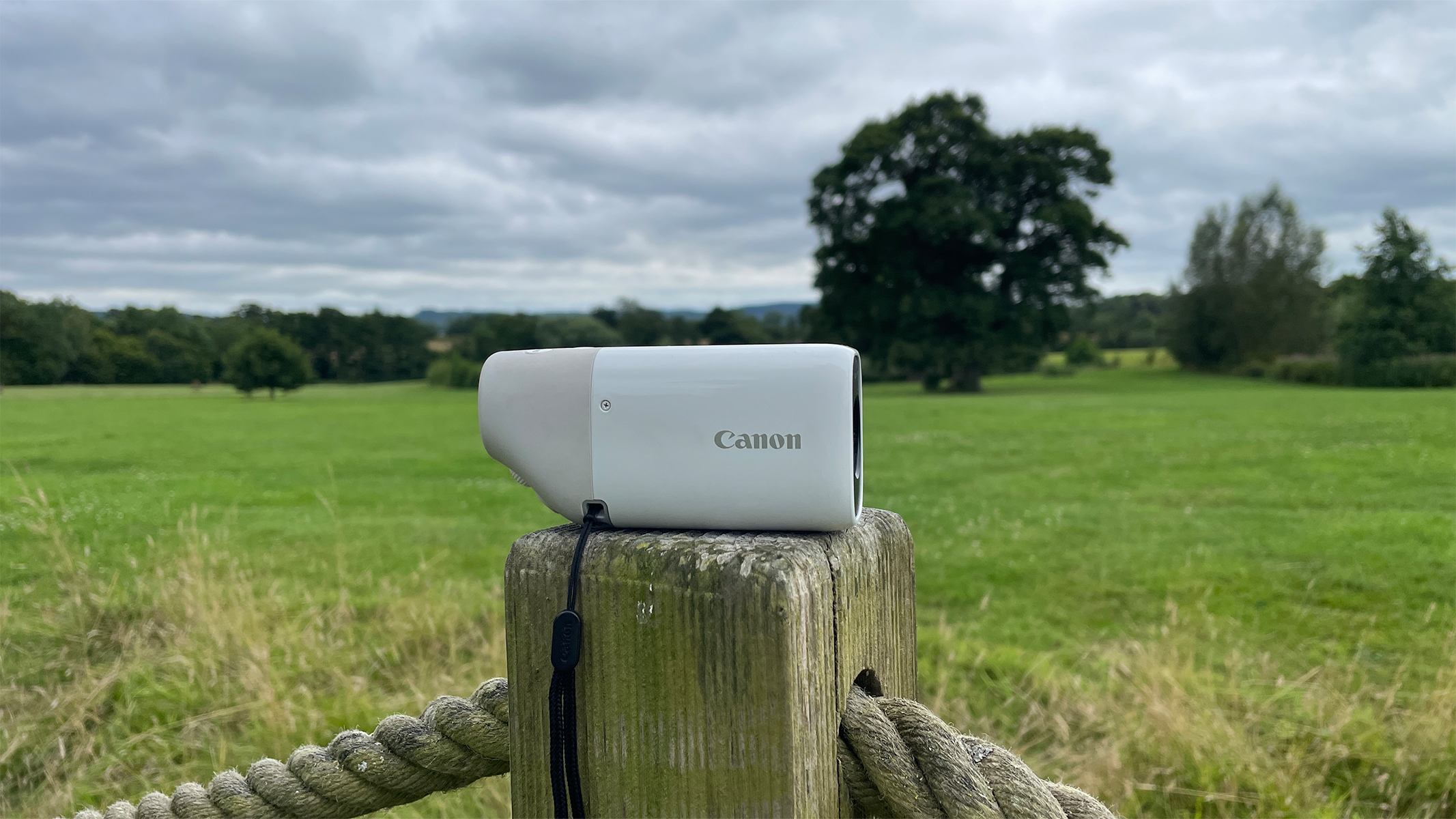 Canon PowerShot Zoom Digital Monocular on a wooden post in a field