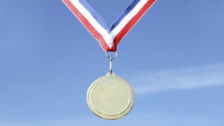 A medal held up against a clear blue sky