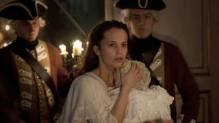 alicia vikander holds a baby next to soldiers in the movie a royal affair