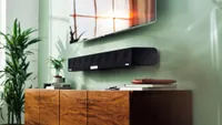 the Sennheiser Ambeo 3D Soundbar mounted on a green wall beneath a TV
