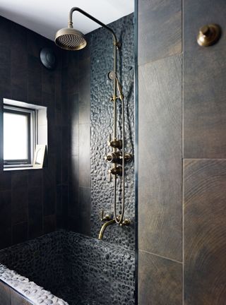 pebbled bath and wall with a brass over the bath shower