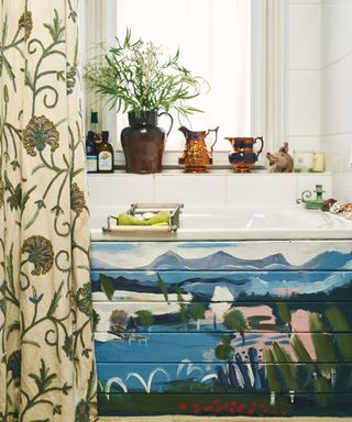 bathroom with floral shower curtain and painted bath panel with seaside scene