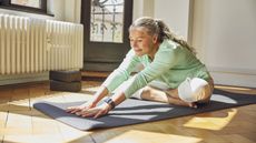 An older woman stretches on her yoga mat.