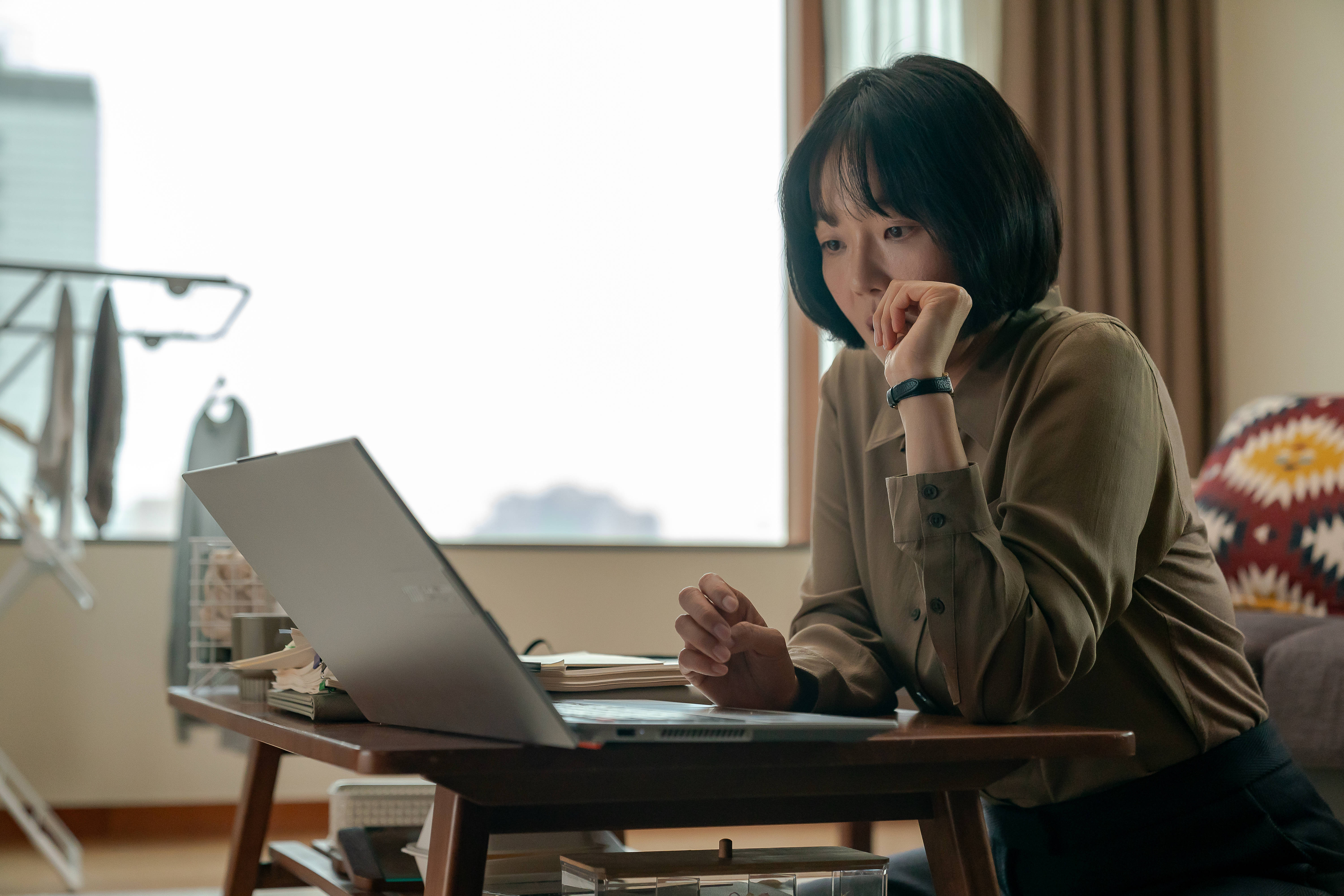 Lee Sang-hee looks at a laptop while sitting on the floor in &#039;Tempest.&#039;