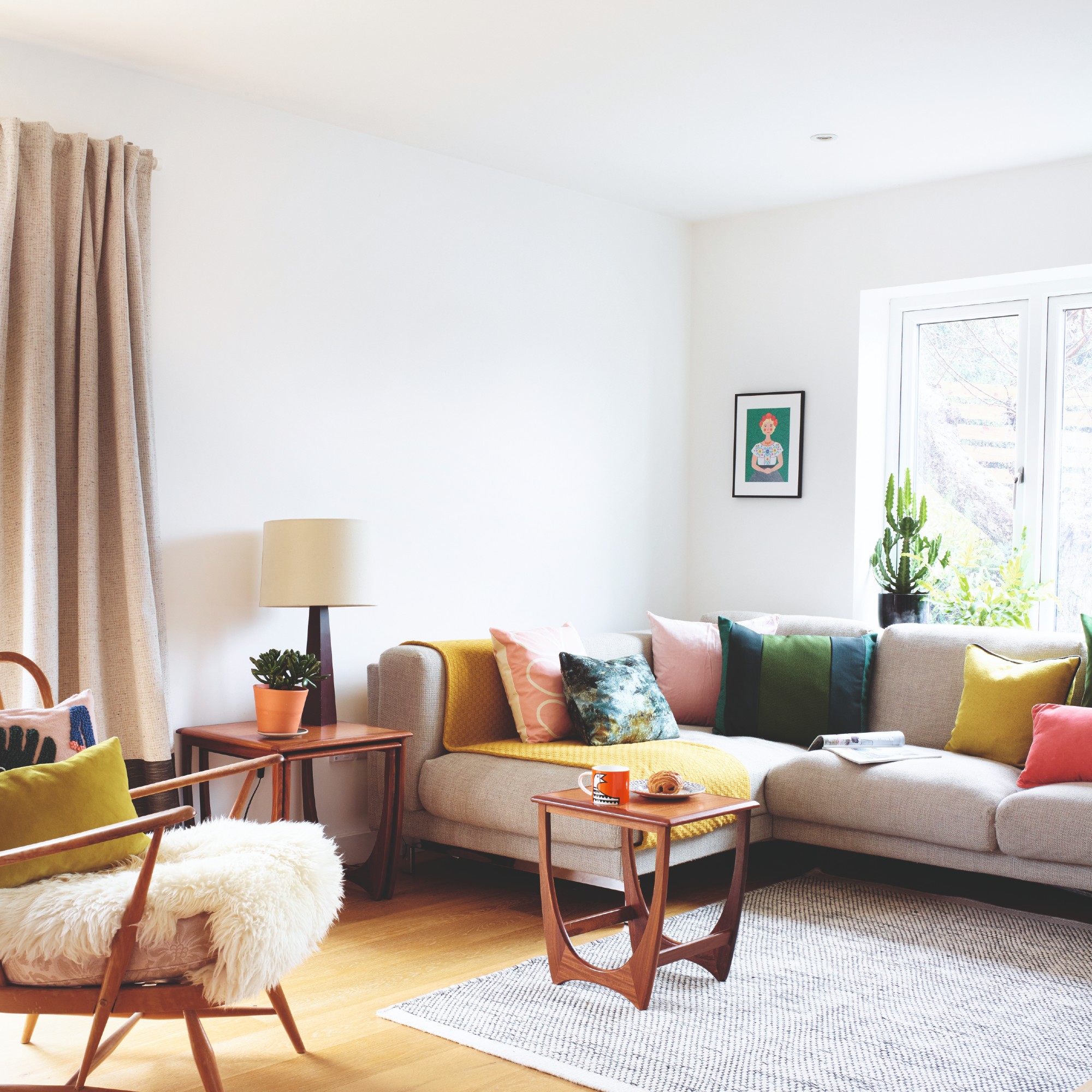 A white living room with a beige corner sofa and midcentury nesting coffee tables