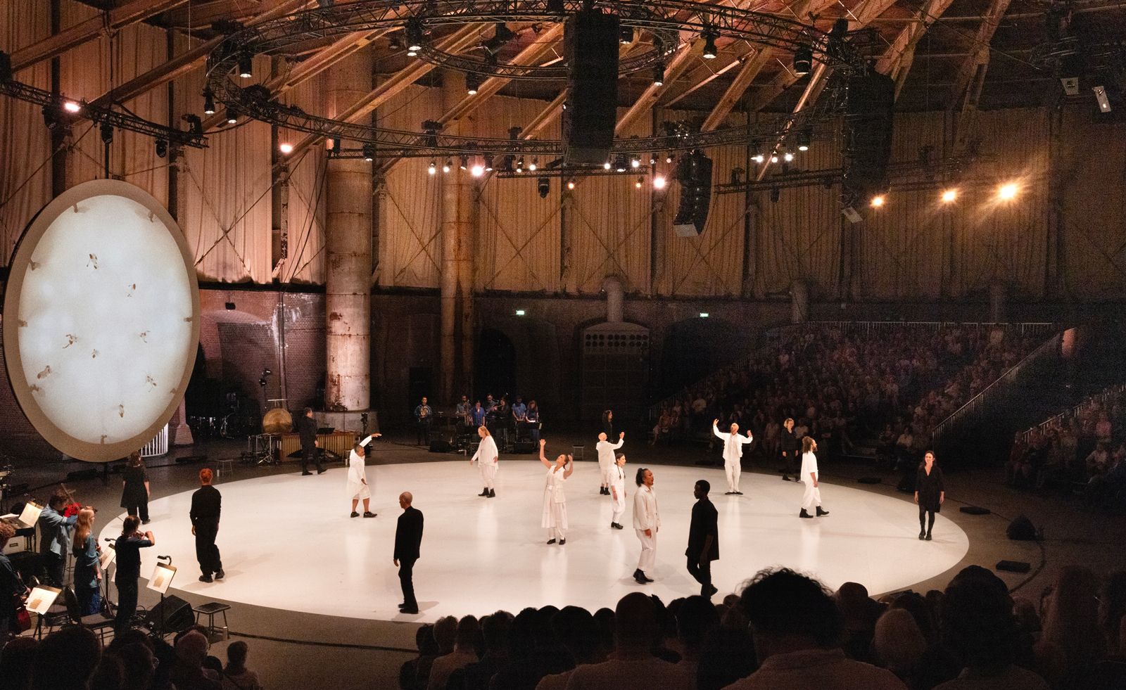 Performers on white circular space, part of Meredith Monk exhibition