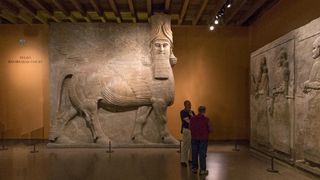 A sculpture of Lamassu in a museum