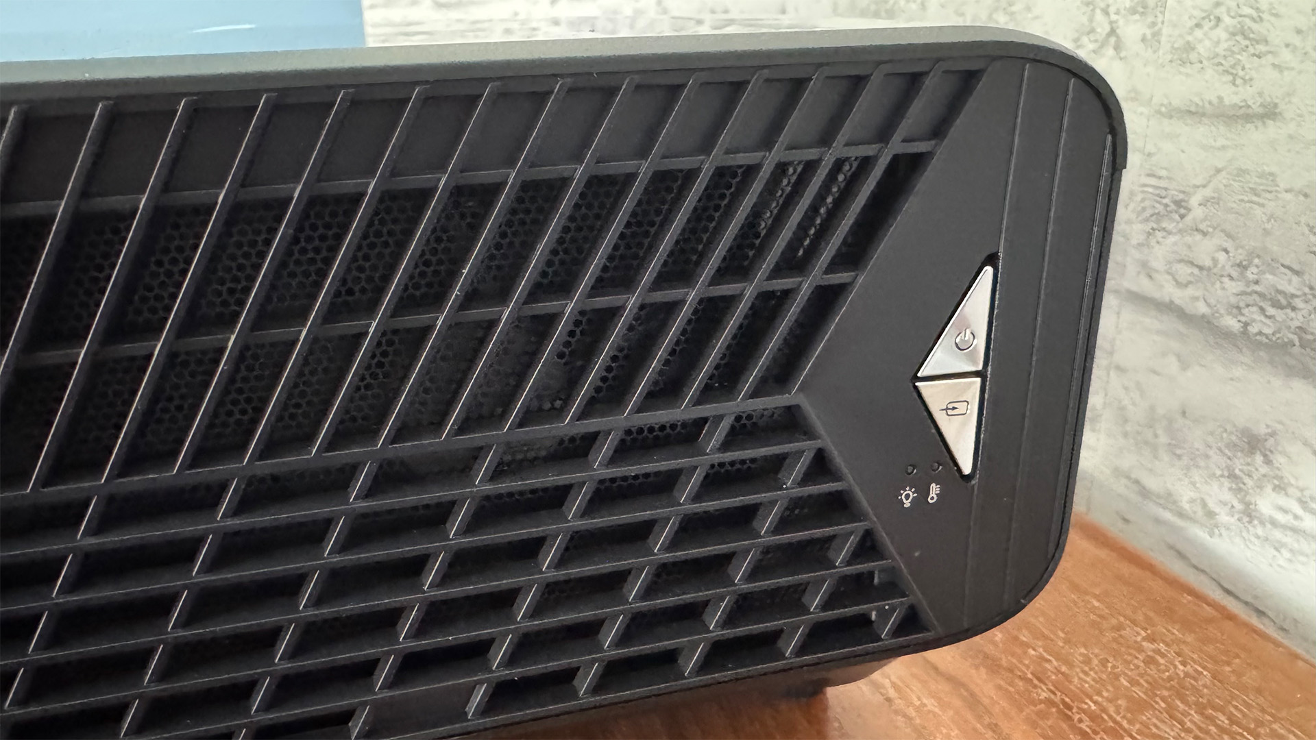 Optoma UHZ68LV home cinema projector detail of side grille, in front of grey brick wall