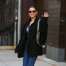 Bella Hadid wearing a black blazer with dark wash denim and a chain handbag