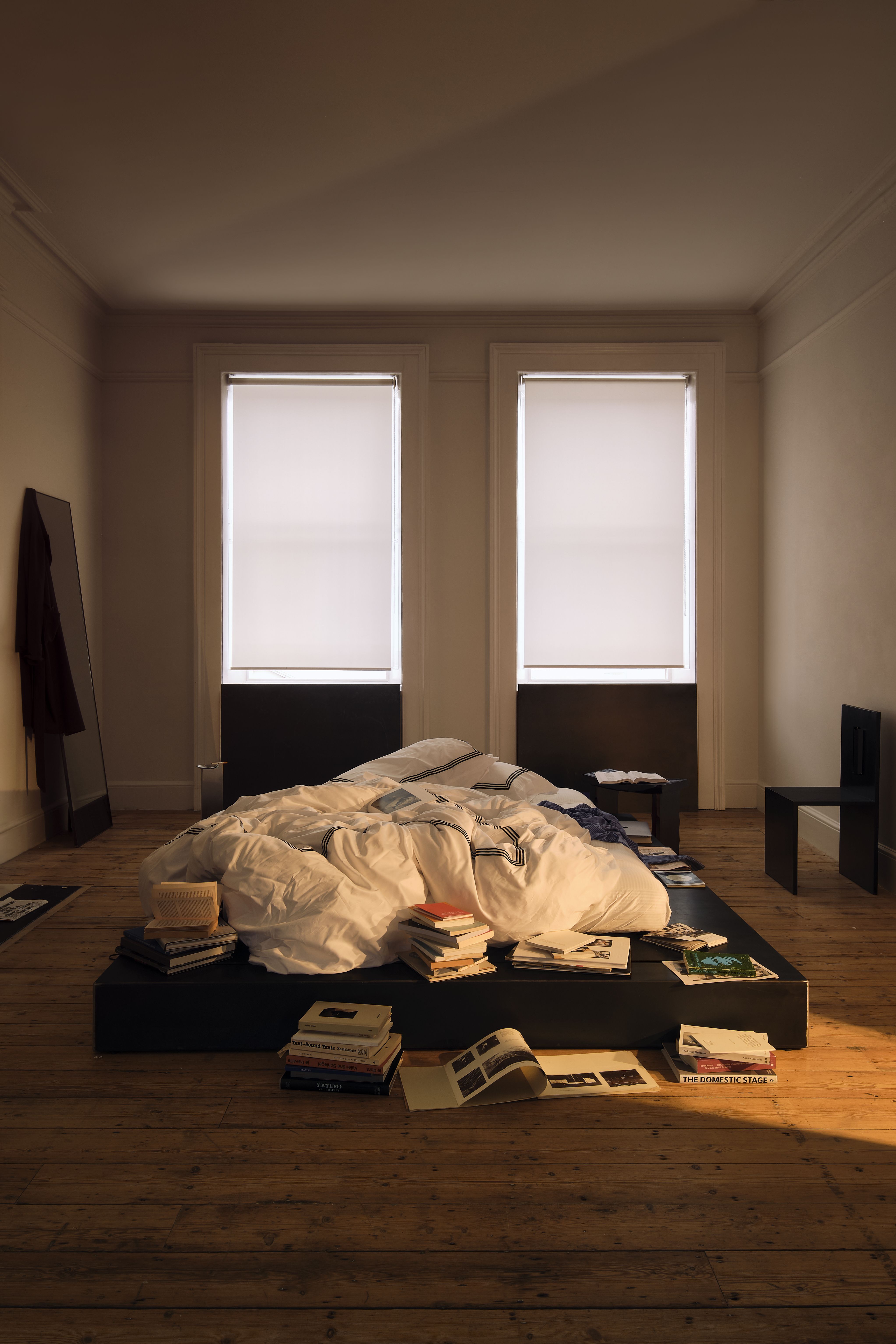 A series of messy interiors, with wooden furniture covered in piles of printed matter, collectibles, leftover food and crockery, and more.