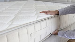 A person checks the firmness levels of a hard mattress