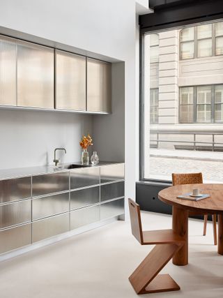 Shiny cabinets and wood table and chairs in Reform Kitchens New York showroom