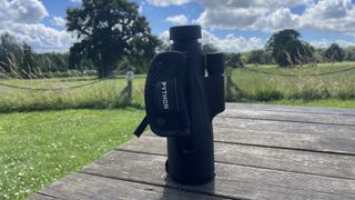 Python 12x52 Range Master Ultra HD Monocular on a wooden table in a park