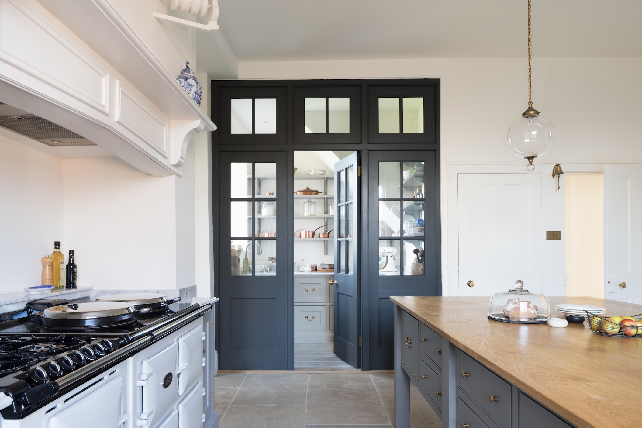 A white kitchen with dark doors through to an under stair walk-in pantry