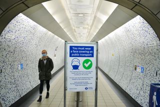 Woman in face mask walking through underground station during tighter lockdown in the UK