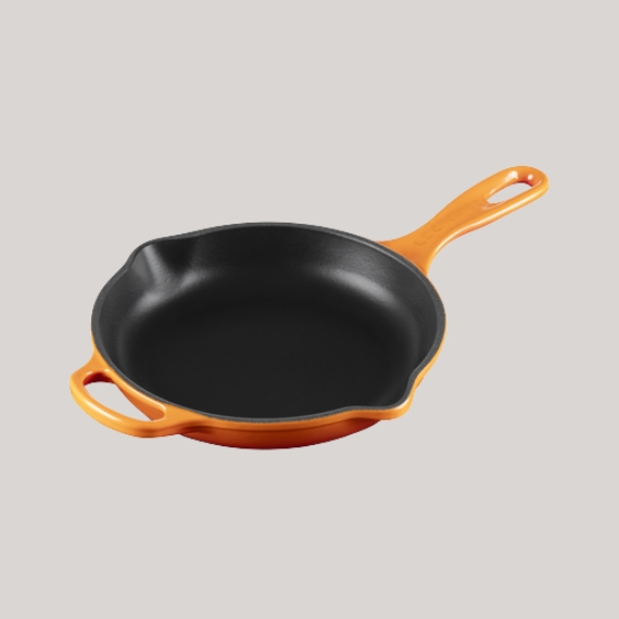 Orange cast-iron pan against a pale grey background.