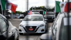 Mexican and American flags are attached on cars at a Tricolor dealership in Houston, Texas