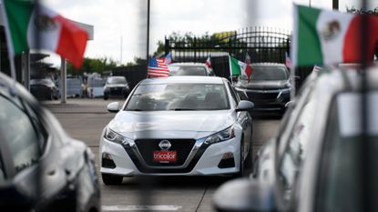 Mexican and American flags are attached on cars at a Tricolor dealership in Houston, Texas