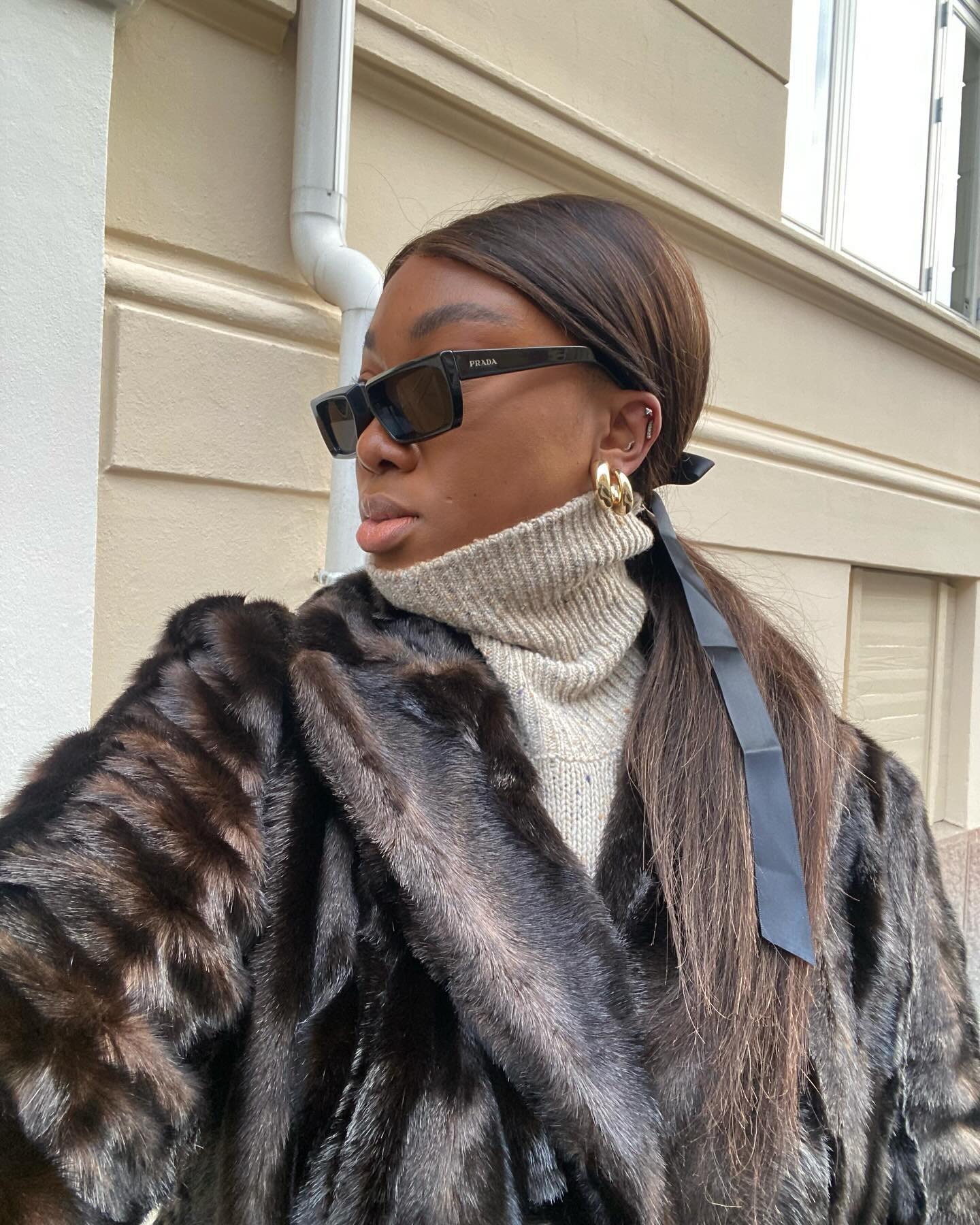 A woman taking a selfie with a ponytail and bow accessory