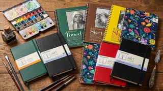 Notebooks and artist sketchbooks on a wooden table
