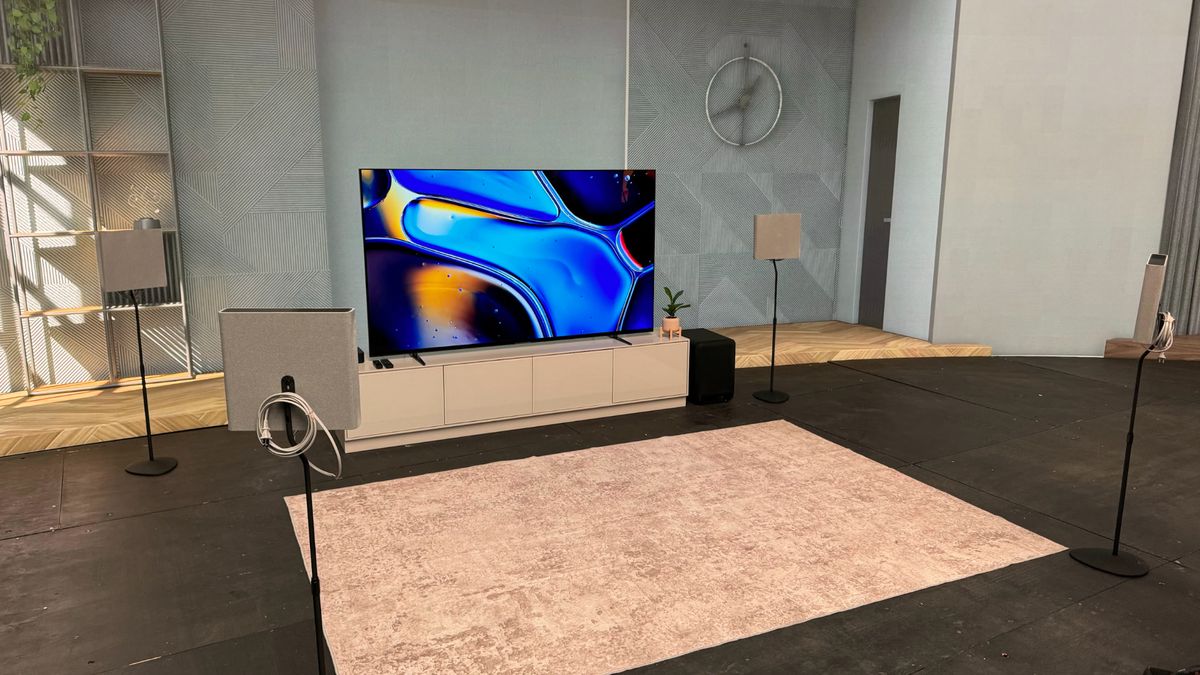 Four Sony Bravia Theatre Quad speakers on stands placed around a rug in front of a TV.