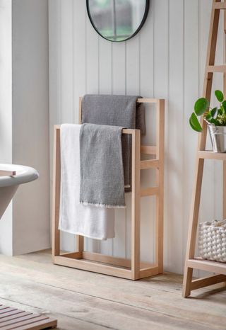 A grey bathroom with a wooden freestanding towel rail