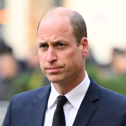 Prince William grimaces while wearing a suit, he has a balding head