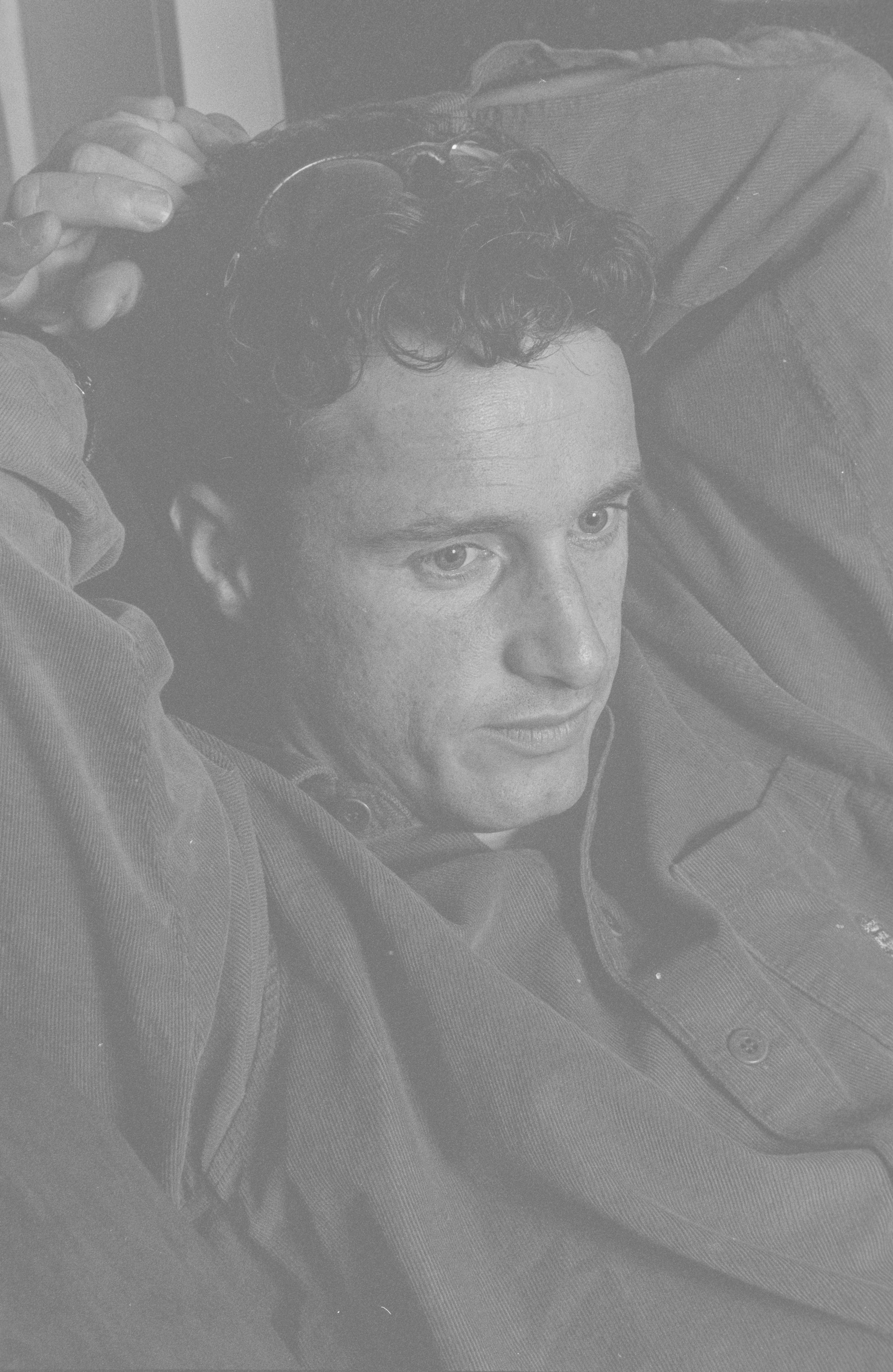 Black and white photograph of Eddie Irvine lounging with his arms behind his head