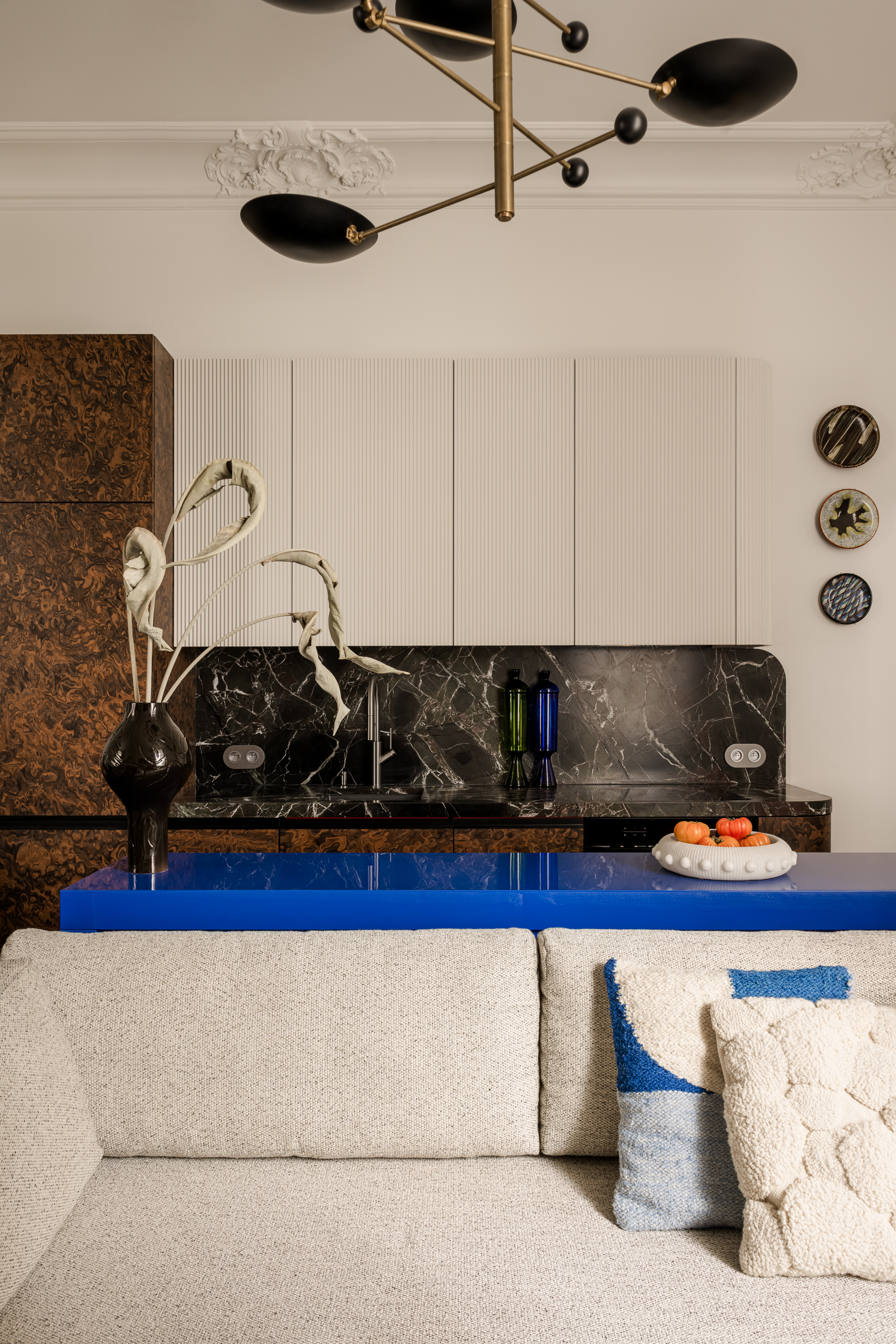 a modern apartment kitchen with burl cabinets, black marble counters and white walls