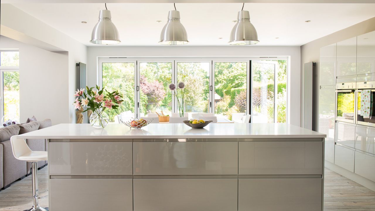 cream coloured kitchen with a row of three chrome pendant lamps hanging above