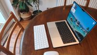 MacBook Pro M5 Max on a dining room table with Apple accessories the Magic Keyboard and Magic Mouse