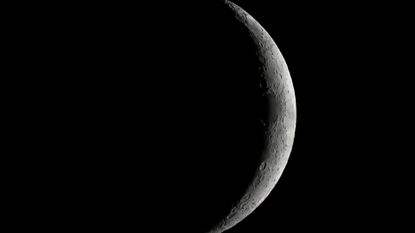 A close up of the moon in the darkness of space, with only it's right outer edge illuminated by the sun.