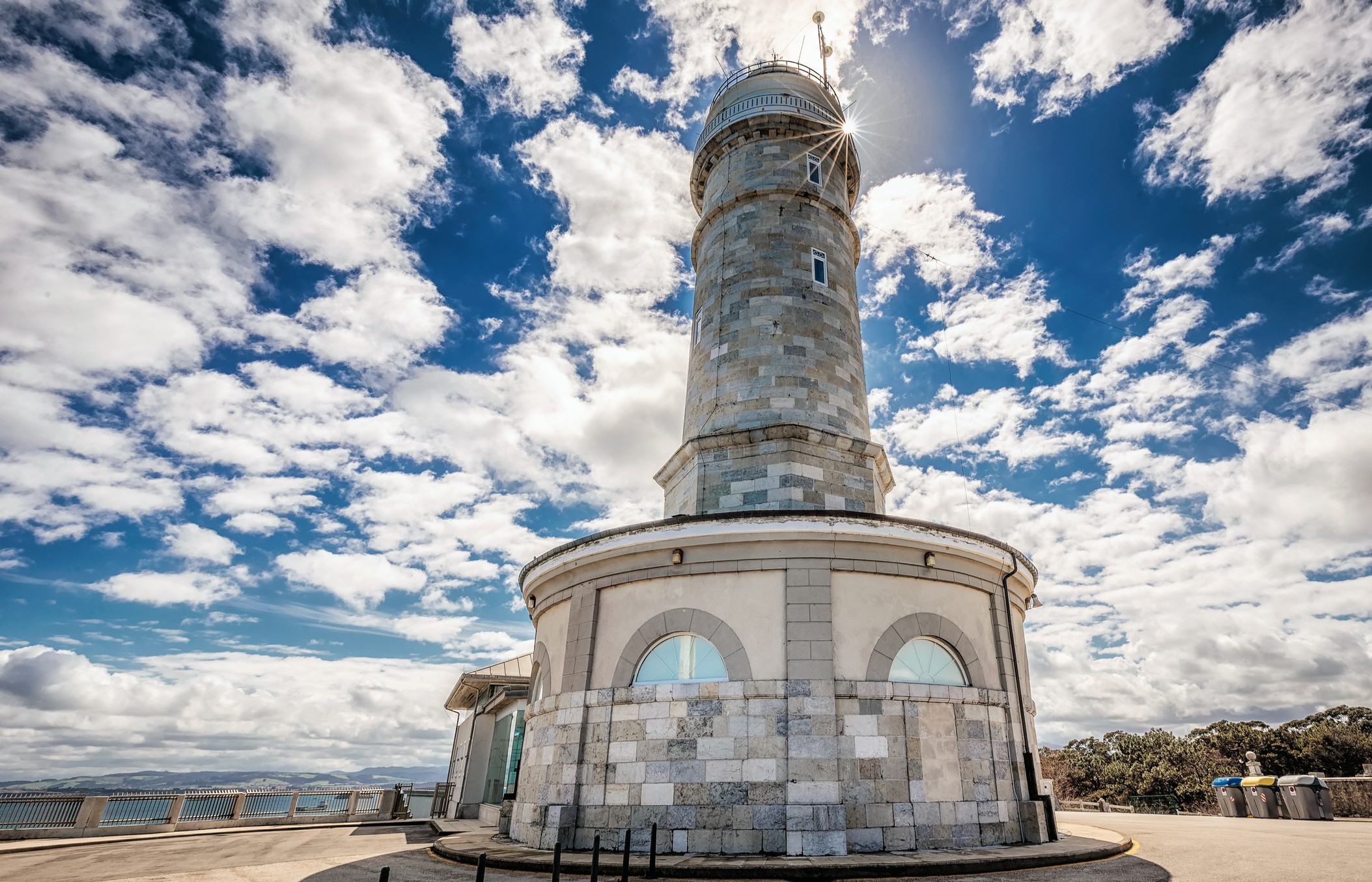a stone lighthouse against a partly cloudy sky.