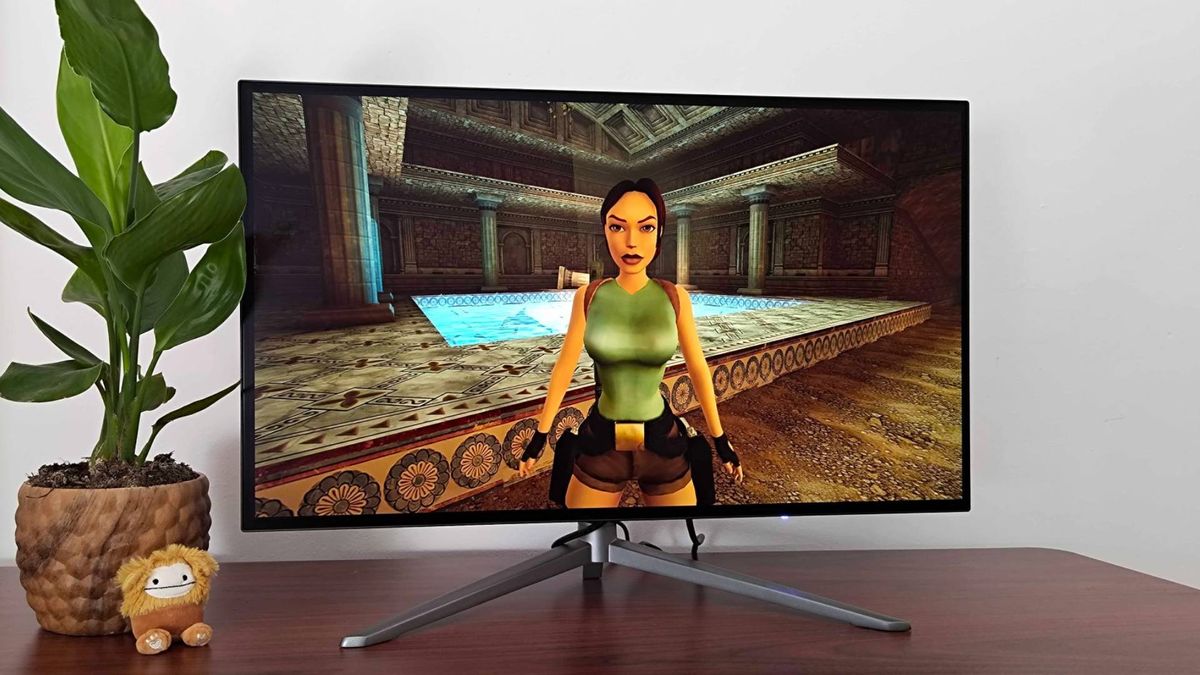 27-inch KTC G27P6 OLED monitor on desk next to plant with Tomb Raider Trilogy gameplay on screen