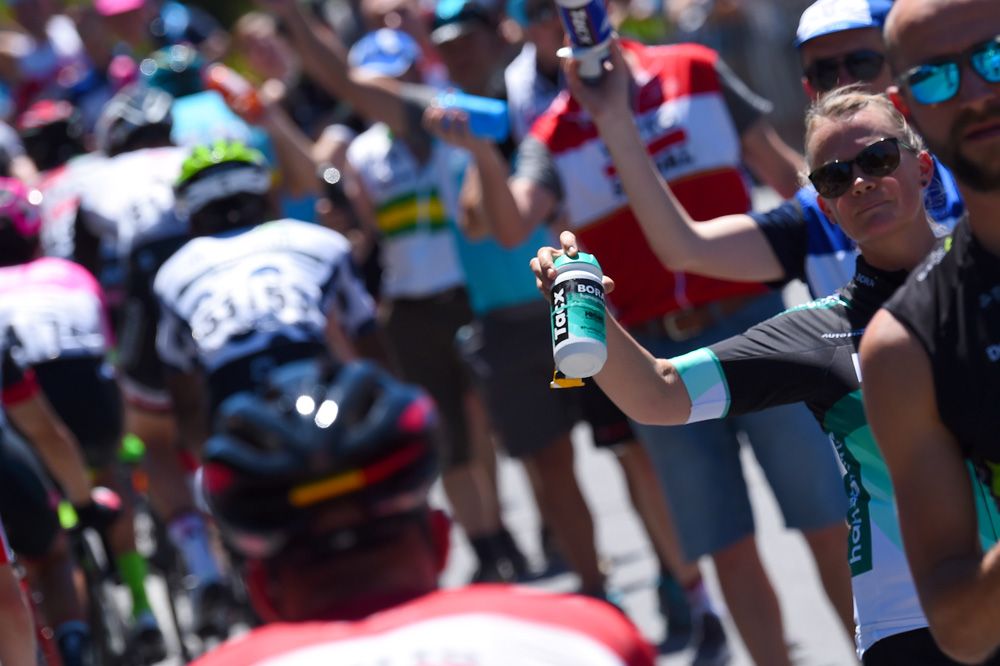 Teams hand up drinks to their rider