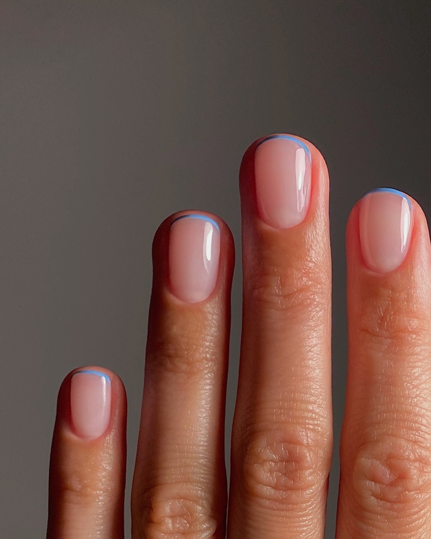 A close-up of a French manicure with a micro-French tips in sky blue