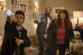 The Doctor (David Tennant) points the sonic screwdriver at the ceiling in Donna's living room, while Shaun (Karl Collins), Donna (Catherine Tate), Sylvia (Jacqueline King) and the Meep step back